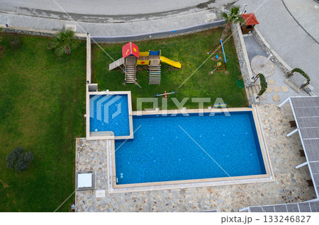 Bright blue swimming pool and playground in a sunny outdoor space near a cozy vacation home 133246827