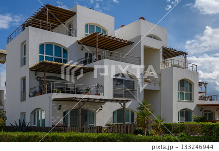 Vibrant white architecture surrounded by lush greenery under a sunny sky 133246944
