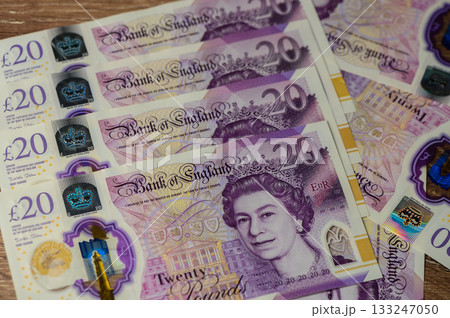 Colorful British currency stacked elegantly on a wooden surface showcasing intricate designs and royalty Colorful British currency stacked elegantly on a wooden surface showcasing intricate designs and royalty 133247050