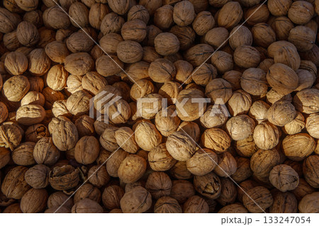 Shelled walnuts gathered on a wooden surface during the harvest season in the sun's warm glow Shelled walnuts gathered on a wooden surface during the harvest season in the sun's warm glow 133247054