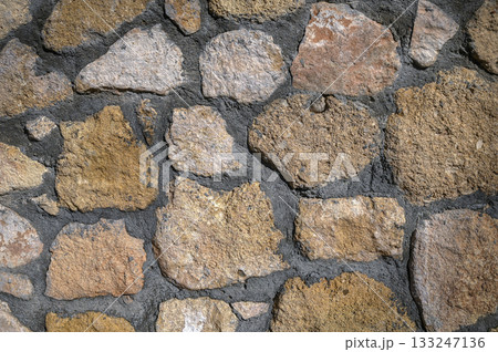 Intricately arranged natural stones create a rustic wall texture in an outdoor setting 133247136