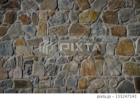 Textured stone wall showcasing earthy tones and natural patterns in a rustic setting 133247143