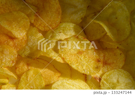 Crispy potato chips arranged delightfully in a satisfying yellow embrace on a bright sunny day Crispy potato chips arranged delightfully in a satisfying yellow embrace on a bright sunny day 133247144