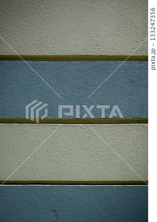Textured wall with alternating bands of color in a modern architectural setting during daylight Textured wall with alternating bands of color in a modern architectural setting during daylight 133247356