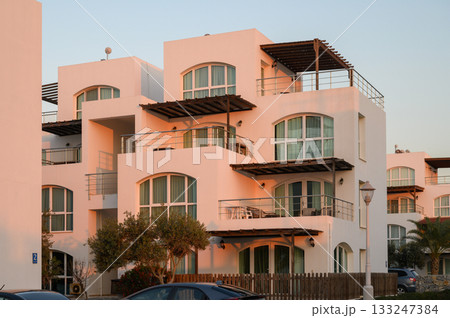 Charming white villas basking in the golden glow of sunset near the coast 133247384