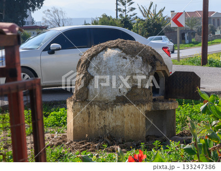 Unique rustic oven stands proud beside a quiet road under the warm sun 133247386