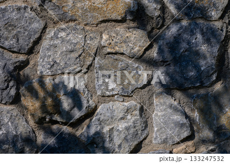 Nature's artistry reveals the beauty of a stone wall under sunlight and shadow Nature's artistry reveals the beauty of a stone wall under sunlight and shadow 133247532