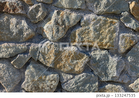 Rustic charm of a weathered stone wall in the heart of a countryside landscape under bright sunlight 133247535