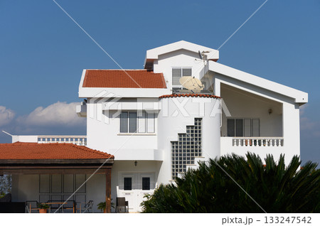 Modern white villa with unique architecture set against a clear blue sky in a tranquil neighborhood Modern white villa with unique architecture set against a clear blue sky in a tranquil neighborhood 133247542