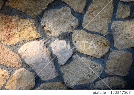Varied textures and colors create a captivating stone wall in natural light near a rustic location Varied textures and colors create a captivating stone wall in natural light near a rustic location 133247567