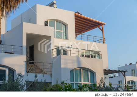 Modern coastal villa basking in evening sunlight with expansive view of tranquil surroundings Modern coastal villa basking in evening sunlight with expansive view of tranquil surroundings 133247684