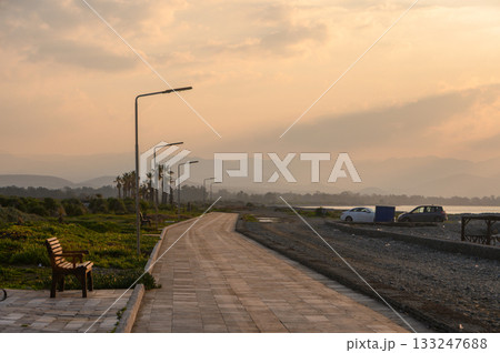 Golden hour captures serene pathway beside the water, inviting quiet contemplation and reflection in nature's embrace 133247688