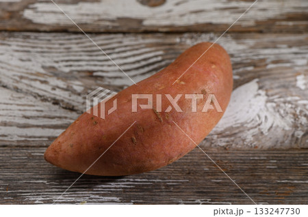 Sweet potato resting on a rustic wooden surface under warm light creating a cozy atmosphere Sweet potato resting on a rustic wooden surface under warm light creating a cozy atmosphere 133247730
