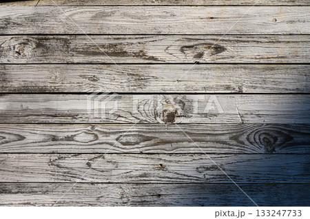 Weathered wood planks create a rustic tapestry of texture and character in warm afternoon sunlight 133247733