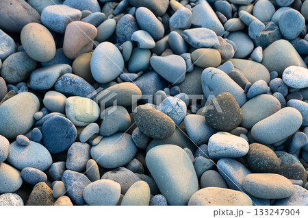 Colorful pebbles scattered along a serene beach at golden hour 133247904