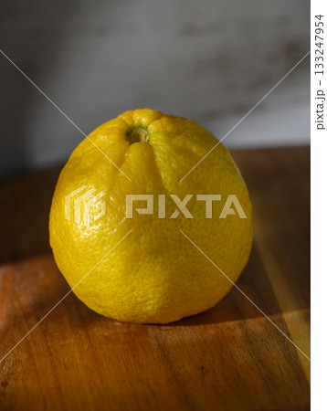 Bright lemon resting on a wooden surface, showcasing its vibrant color and texture in soft light 133247954