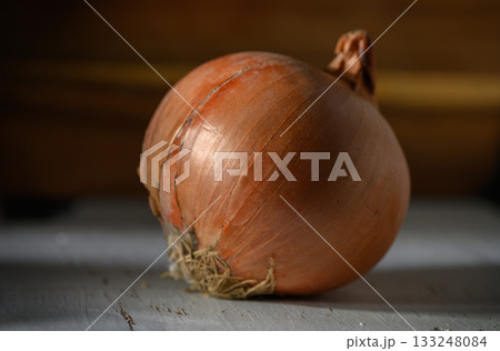 Fresh and vibrant onion resting on a rustic wooden surface after being harvested in the late afternoon light 133248084