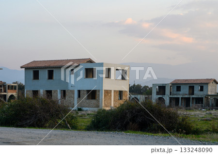 Deserted buildings stand quietly under a soft sunset sky in a forgotten development 133248090