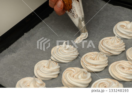 Beautifully crafted meringue swirls form an exquisite dessert display in a cozy kitchen 133248193