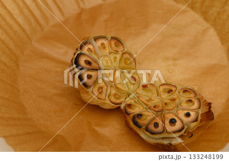 Deliciously roasted garlic bulbs showcasing their warm golden tones on parchment paper 133248199