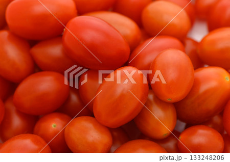 Fresh cherry tomatoes piled together showcasing vibrant red hues in a sunlit kitchen 133248206
