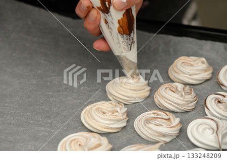 Creating delicate meringue swirls in a cozy kitchen setting during a baking session 133248209