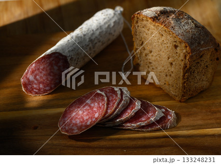 Artisan cured meat and fresh bread on a rustic wooden cutting board in soft afternoon light 133248231