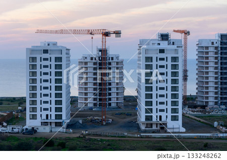 New residential towers rise against a coastal sunset skyline in a developing urban area near the sea New residential towers rise against a coastal sunset skyline in a developing urban area near the sea 133248262