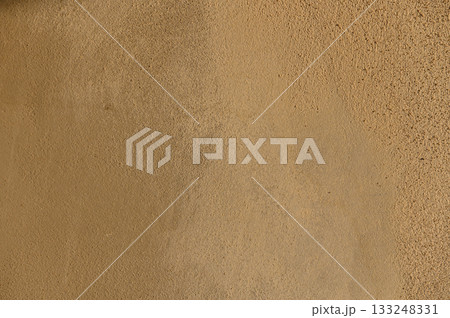 Texture of warm earth tones on a sunlit wall evokes a sense of calm and natural simplicity 133248331