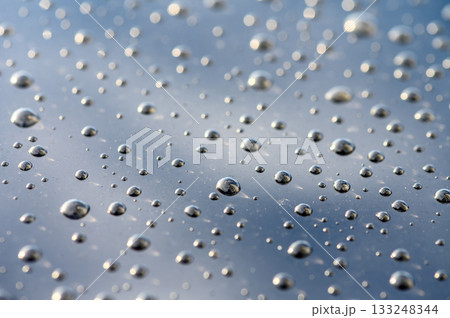 Raindrops dance on a reflective surface under a cloudy sky during a tranquil moment of nature Raindrops dance on a reflective surface under a cloudy sky during a tranquil moment of nature 133248344