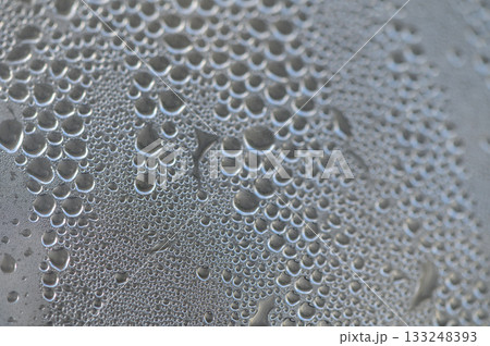Dewdrops glisten on a dark surface under the soft light of dawn, creating a delicate atmospheric beauty Dewdrops glisten on a dark surface under the soft light of dawn, creating a delicate atmospheric beauty 133248393