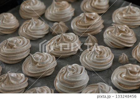 Delicious swirls of meringue cooling on parchment in a cozy kitchen 133248456