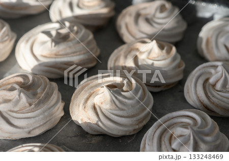 Delicious meringues with a glossy finish tempt dessert lovers in a cozy kitchen setting 133248469