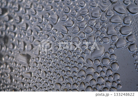 Raindrops gather on a window pane, creating a mesmerizing pattern of nature's artwork at dawn Raindrops gather on a window pane, creating a mesmerizing pattern of nature's artwork at dawn 133248622