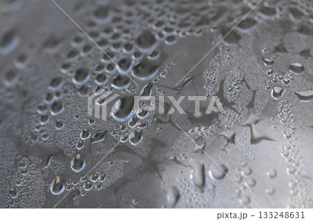 Droplets of water glisten on a metallic surface after a refreshing rain shower at dawn 133248631