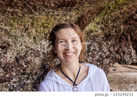 Caucasian female smiling in front of rocky cliff wearing white shirt Caucasian female smiling in front of rocky cliff wearing white shirt 133249231