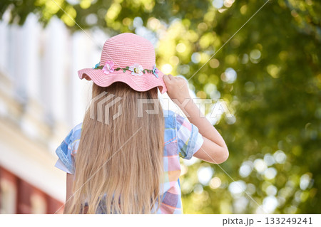Caucasian young girl in pink hat enjoying summer outdoors amidst greenery Caucasian young girl in pink hat enjoying summer outdoors amidst greenery 133249241