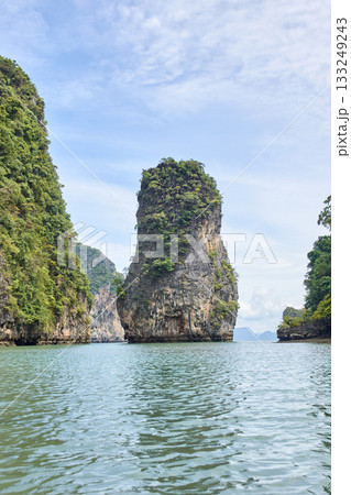 Majestic limestone island rising from clear blue waters with lush greenery 133249243