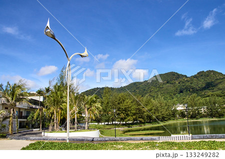Lamp post against mountainous backdrop with blue sky and lush greenery Lamp post against mountainous backdrop with blue sky and lush greenery 133249282