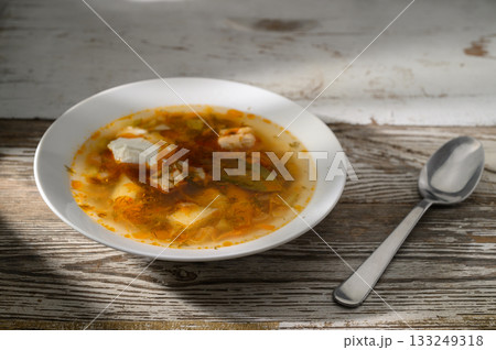 Warm soup bursting with flavors served in a rustic bowl on a wooden table 133249318