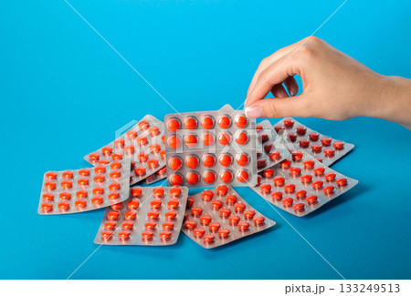 Blister pack with red pills in a female hand on a blue background. Concept of statin pills for lowering cholesterol in the blood. Copy space for text, bile acid sequestrants Blister pack with red pills in a female hand on a blue background. Concept of statin pills for lowering cholesterol in the blood. Copy space for text, bile acid sequestrants 133249513