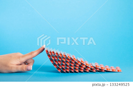 Red antibacterial tablets and female hand on blue background. Concept of medicinal tablets in phaomaceuticals. Copy space for text, antiinflammatory 133249525