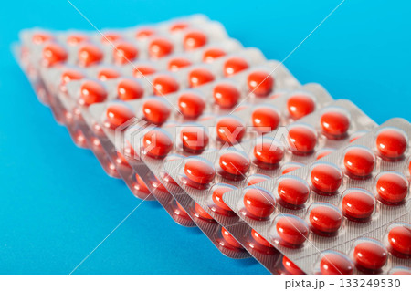 Blisters with red pills on a blue background. Concept of a biologically active food supplement in pharmaceuticals, close-up. Copy space for text Blisters with red pills on a blue background. Concept of a biologically active food supplement in pharmaceuticals, close-up. Copy space for text 133249530