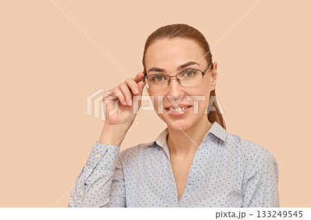 Caucasian female adult with glasses smiling in blue polka dot shirt against 133249545