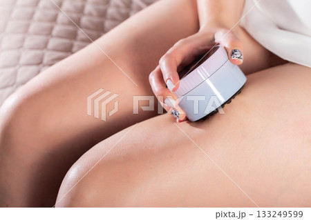 The girl does an anti-cellulite massage on her legs with a portable vacuum massager. Getting rid of flabby skin and cellulite, close-up, effective 133249599