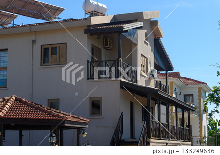 Bright sunny day highlighting a charming residential building surrounded by lush greenery and clear blue skies in a serene neighborhood 133249636