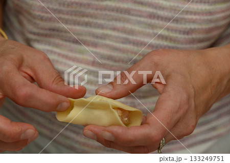 Hands skillfully folding a delicious dumpling in a cozy kitchen setting during a sunny afternoon 133249751