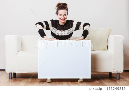 woman on sofa holding blank presentation board. woman on sofa holding blank presentation board. 133249813