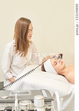 Female esthetician performing facial treatment on young caucasian woman in spa Female esthetician performing facial treatment on young caucasian woman in spa 133249899