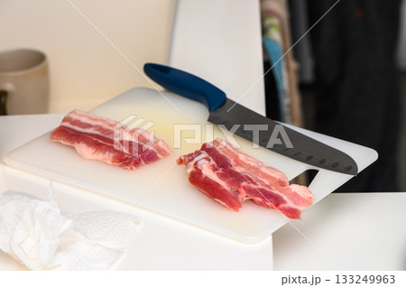 Slicing fresh cuts of meat in a modern kitchen during midday culinary preparation Slicing fresh cuts of meat in a modern kitchen during midday culinary preparation 133249963